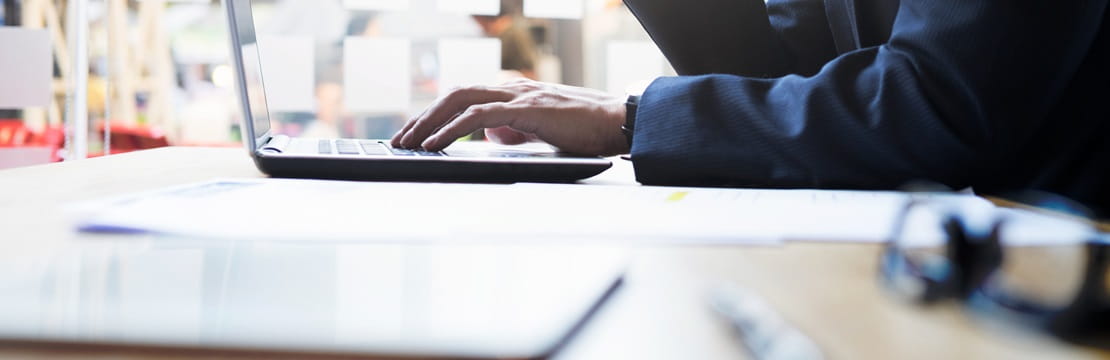 Seated man reading his laptop computer.